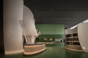 Modern restaurant interior with a large green wall, metal counter, and potted plant, featuring a welcoming atmosphere