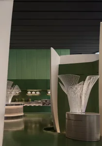 Modern restaurant interior with green walls, white columns, and decorative vases and bowls