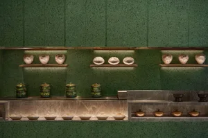 A clean and organized kitchen with green walls and a countertop featuring variously sized bowls and two cups, emphasizing functionality and practicality