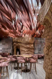 Modern restaurant interior with wooden walls, tables, chairs, and bar stools, creating a warm and inviting atmosphere