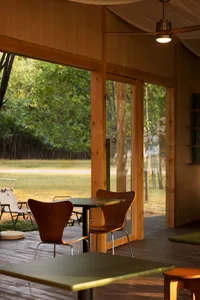 Warm and inviting open concept living area with wooden walls and floors, featuring a dining table and three chairs, and natural light from windows