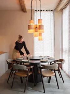 A round dining table surrounded by chairs, set for a dinner party with wine glasses and cups, creating a warm and inviting atmosphere for socializing and enjoying food together