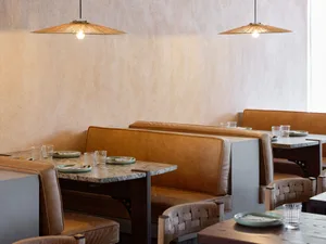 A warm and inviting restaurant interior with beige walls, dining tables, chairs, and cups, creating a comfortable atmosphere for diners