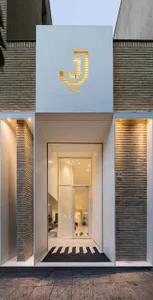 A welcoming entrance with a large glass door, two potted plants, and a well-lit interior
