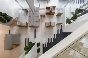 A modern lounge space with multiple seating areas on different levels, featuring chairs and potted plants, creating a comfortable and inviting atmosphere