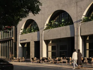 A building with an archway leading to a courtyard, featuring variously sized chairs in a welcoming outdoor-indoor space