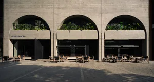 Architectural scene of two buildings with large arches adorned with greenery, featuring chairs and potted plants