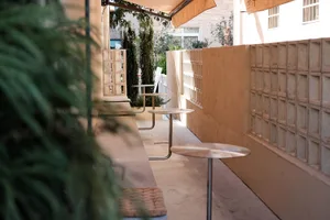 A patio area with three dining tables and chairs under umbrellas, creating a shaded and inviting outdoor space for socializing and meals