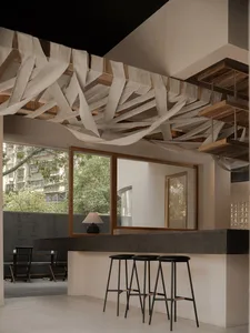 A well-lit restaurant bar area with a wooden counter, stools, and chairs, surrounded by inviting decor
