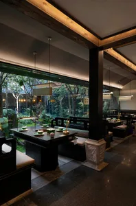Warm and inviting Asian restaurant interior with wooden elements, stone flooring, and dining tables set for guests