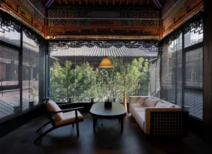 Asian-style living room with a large window, two couches, a chair, a dining table, and a potted plant, creating a warm and inviting atmosphere with a focus on comfort and relaxation