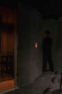 A man in a suit stands in front of a doorway in a room with two chairs, creating an elegant and sophisticated atmosphere