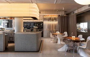 Modern open kitchen with a bar counter, chairs, and wine glasses, featuring a warm and inviting atmosphere