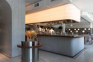 A modern restaurant bar with a countertop, wine glasses, and bottles displayed in a sophisticated and inviting atmosphere