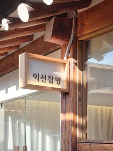 A well-lit Asian restaurant with wooden walls, a glass door, and Chinese writing on a sign