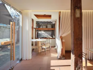 Warm and inviting dining space with wooden elements, two tables, and chairs, creating a rustic atmosphere