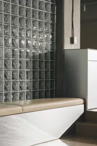 A modern interior design featuring a glass and wood bench in front of a glass block wall, creating a calm and inviting atmosphere with a sense of openness