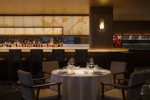 Sophisticated restaurant interior with a dining table, chairs, wine glasses, and bottles, set for dinner service