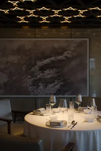 A luxurious dining area with a large table set for a meal, surrounded by chairs, wine glasses, and fine china