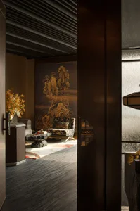 A warm and inviting Asian-inspired living area with a large wooden doorway, two couches, a chair, and a vase, creating a comfortable and relaxing space