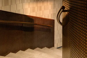 A real staircase in a building with a wooden staircase, a metal object on the right, and a wall in the background, suggesting a functional yet aged design