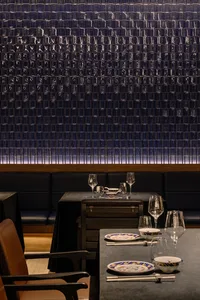 A modern restaurant interior with glass block walls, tables, chairs, and wine glasses, creating a stylish and inviting atmosphere