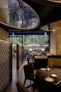 A restaurant dining area with a large table, multiple chairs, and umbrellas providing shade and ambiance