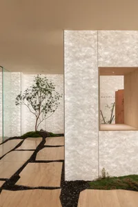 A clean and inviting indoor space with white walls, stone-like finish, and several potted plants
