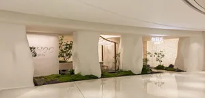A calm and inviting space with a white rock wall divider, a dining table, potted plants, and decorative vases