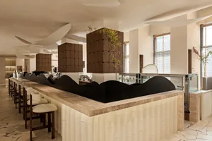 A modern restaurant bar with a black countertop, white walls, and comfortable seating around a dining table