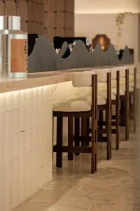 Warm and inviting bar area with wooden stools and tables, black countertop, and multiple chairs for socializing