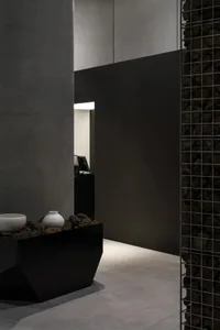 A modern hallway with white walls, a doorway, and decorative vases and a bowl, set against a neutral background