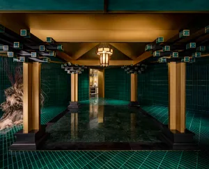 Ornate bathroom with a large tiled floor featuring a checkered pattern in green and gold tones, adorned with gold accents and intricate patterns