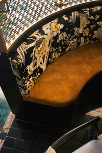 Ornate bench with floral design in a living area, possibly a dining room, with a black frame and Asian-inspired aesthetic