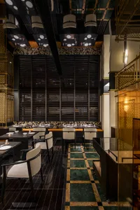 Sophisticated dining space with white tablecloths, black and gold walls, and comfortable seating for guests