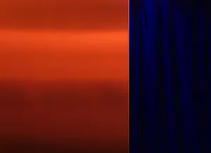 A modern interior space with an orange metal wall and a blue curtain, creating a striking contrast between the two colors