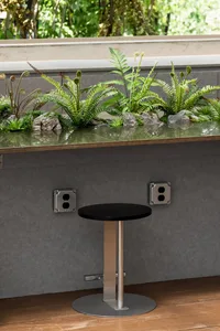 A cozy indoor space with a wooden countertop, potted plants, and lush greenery