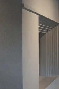 Interior space with a white doorframe and gray wall, open doorway revealing a hallway beyond, clean and minimalist design