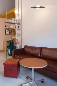 A modern living room with a brown leather couch, two chairs, and a dining table in a white walled space with a comfortable atmosphere