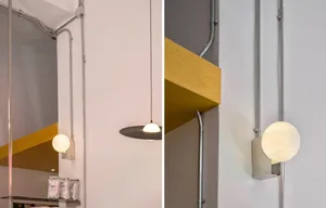 A kitchen or dining area with hanging lights, a yellow shelf on a white wall, and bottles on a shelf