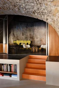A well-lit dining area with a table and chairs, surrounded by a bookshelf and natural or artificial light sources
