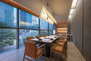 A restaurant interior with a large wooden dining table surrounded by multiple chairs, creating an inviting atmosphere for socializing and dining
