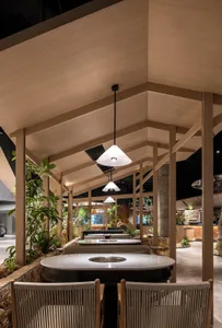Dining area with wooden tables, chairs, and potted plants, creating a warm and inviting atmosphere
