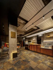 A cozy restaurant with a brick wall, wooden furniture, and metal accents, featuring a mix of modern and traditional elements, with various lighting sources creating a warm ambiance