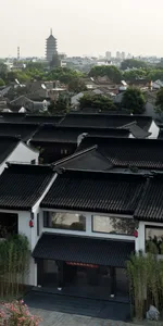 A serene Asian cityscape featuring traditional homes with black roofs, arranged in rows, showcasing intricate details and a calm atmosphere