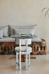 Cozy living space with a dining table and chairs, surrounded by a couch and decorated with cups and bowls