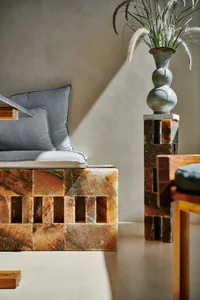 Cozy bedroom with a stone wall, marble bench, and natural materials, featuring a modern and elegant style