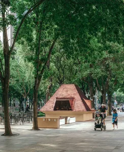 Outdoor area with benches, chairs, and a bicycle, surrounded by people enjoying a casual atmosphere