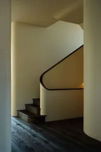 A warm and inviting interior staircase with two sets of wooden steps in a spiral pattern
