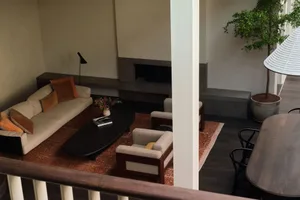 A cozy living area with a couch, chairs, dining table, and potted plants, set against a neutral background